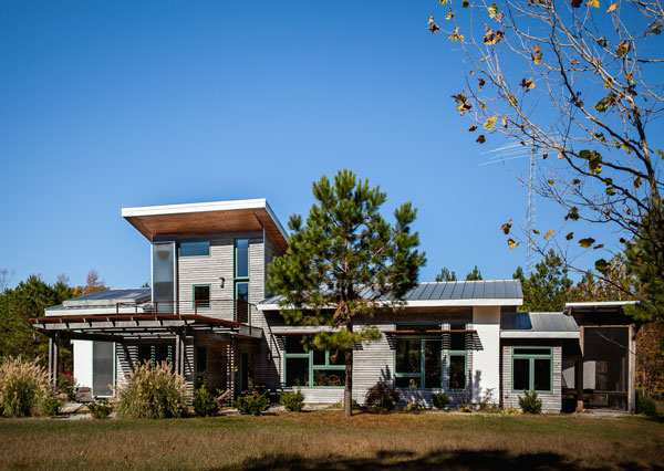 Bob's net zero Home: Back view with large windows, solar panels and trellis.